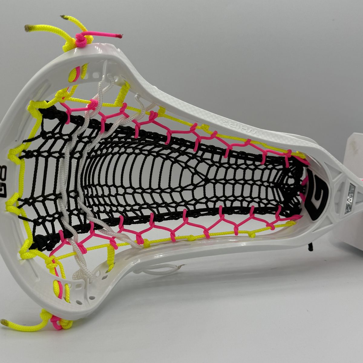 Close-up of a lacrosse head with white, black, pink, and yellow strings on a gray background
