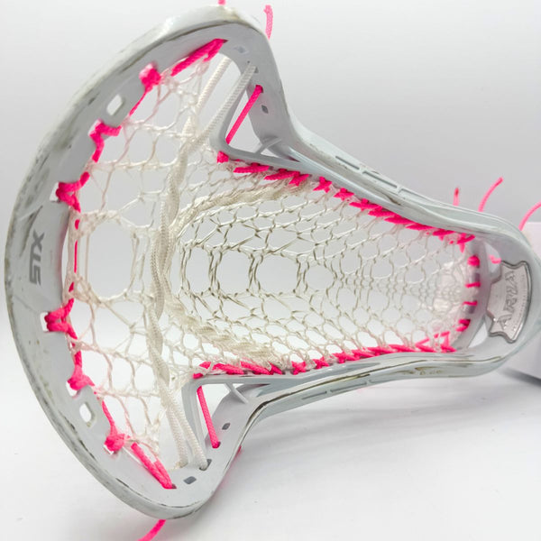 A close-up of a white lacrosse head with white mesh and bright pink thread accents, photographed on a clean white background.