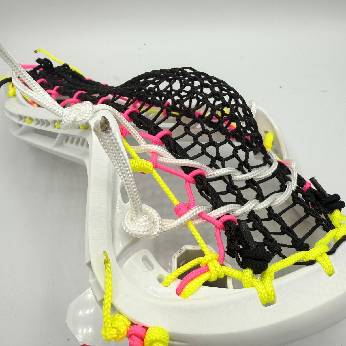 Close-up of a lacrosse head with colorful stringing on a white background