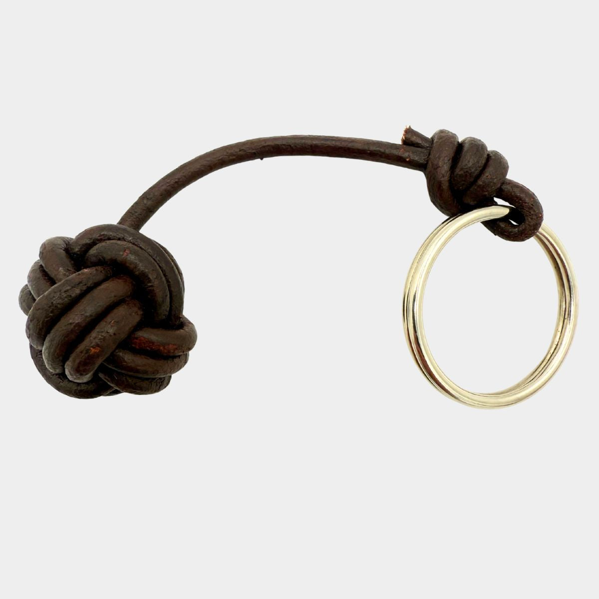 Brown leather knot Monkey’s Fist keychain with a gold ring on a white background