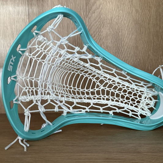 Teal lacrosse head with white strings on a wooden surface